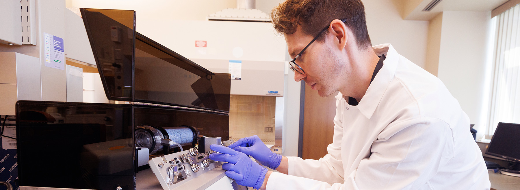 researcher inserting a specimin slide into equipment for review